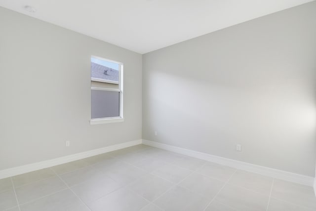 spare room featuring light tile patterned floors and baseboards