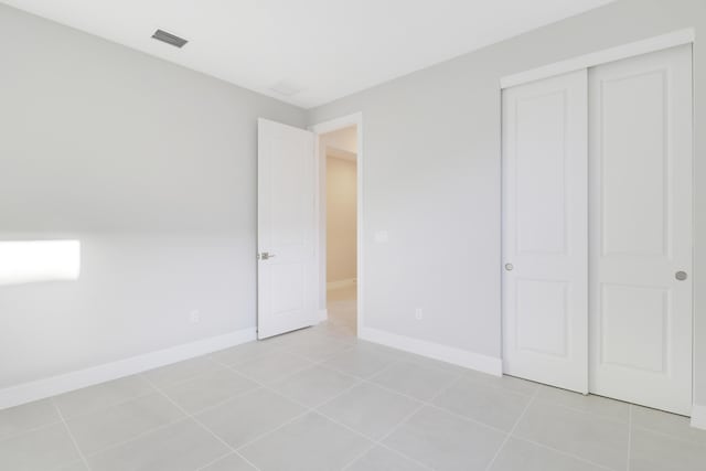 unfurnished bedroom featuring a closet, visible vents, baseboards, and light tile patterned floors