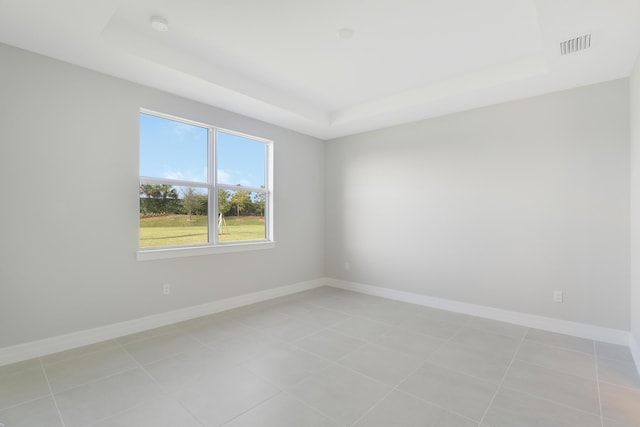 empty room featuring a raised ceiling, visible vents, baseboards, and light tile patterned floors