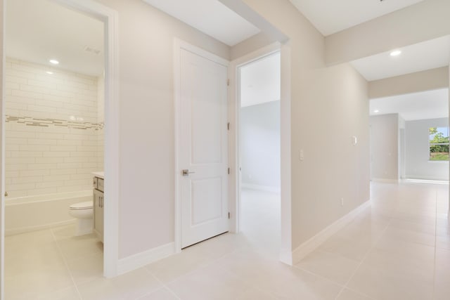 corridor featuring light tile patterned floors, baseboards, and recessed lighting