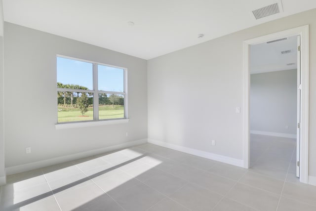 empty room with visible vents, baseboards, and light tile patterned floors