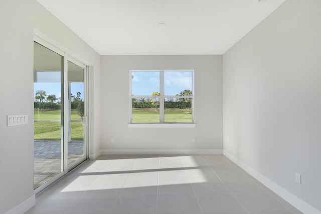 tiled spare room featuring baseboards