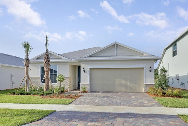 view of front facade with decorative driveway, stone siding, a garage, and stucco siding