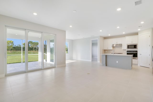 unfurnished living room with a sink, visible vents, and recessed lighting