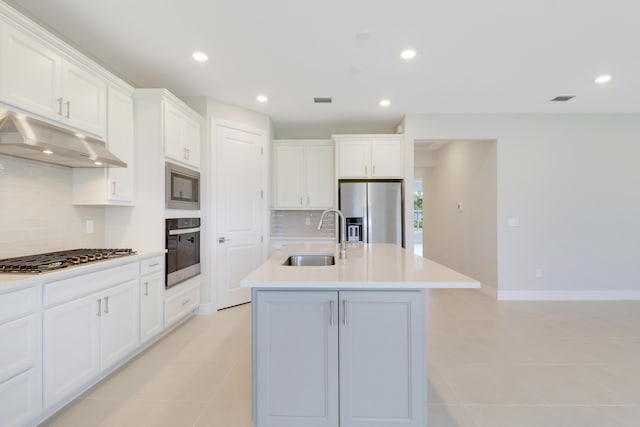 kitchen featuring a center island with sink, stainless steel appliances, under cabinet range hood, white cabinetry, and a sink