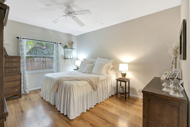 bedroom featuring light wood-style flooring, a ceiling fan, and baseboards