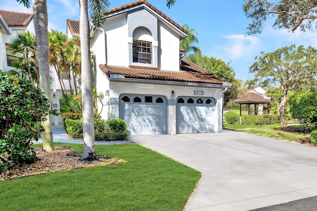 mediterranean / spanish house with a tiled roof, a front lawn, driveway, and stucco siding