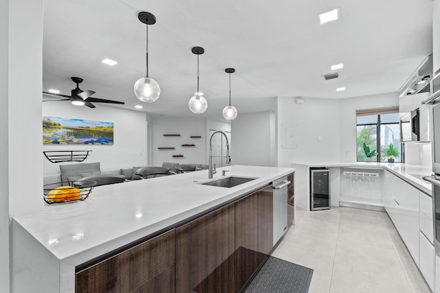 kitchen with wine cooler, modern cabinets, light countertops, and a sink