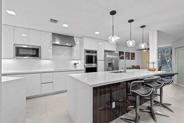 kitchen featuring white cabinetry, wall chimney exhaust hood, modern cabinets, and appliances with stainless steel finishes