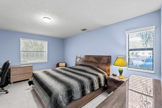 bedroom with visible vents, a textured ceiling, and tile patterned floors