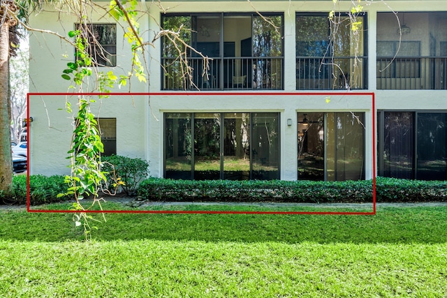 view of exterior entry with a lawn and stucco siding