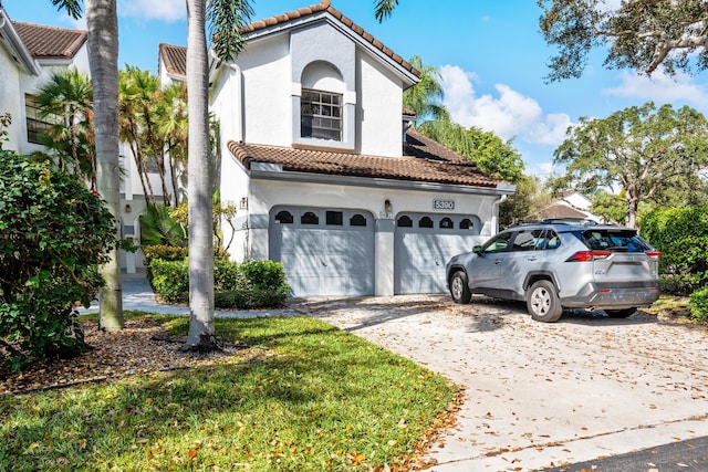 mediterranean / spanish home featuring driveway, a tile roof, a garage, and stucco siding