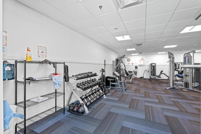 exercise room featuring visible vents, a drop ceiling, and carpet flooring