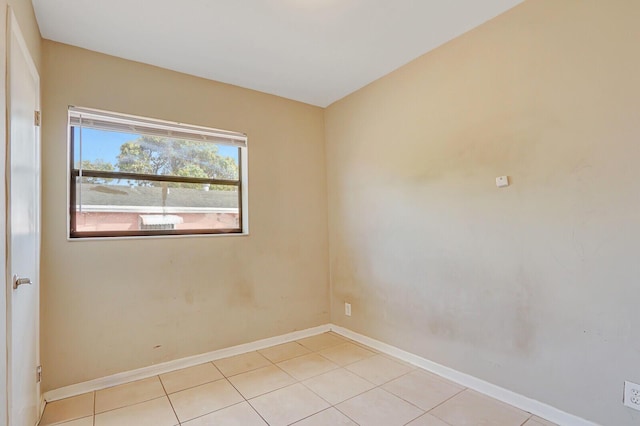 empty room with light tile patterned floors and baseboards