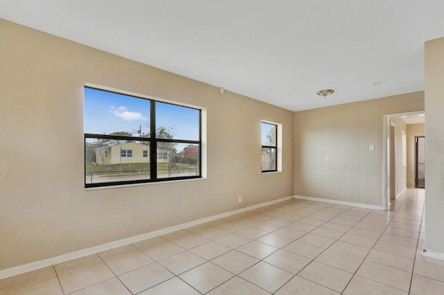 empty room featuring baseboards and light tile patterned floors