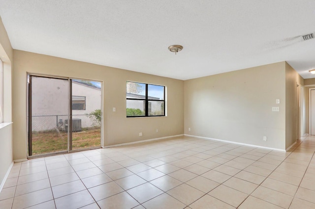 spare room with light tile patterned floors, baseboards, and a textured ceiling