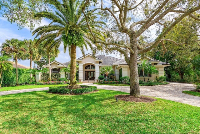 7500 Marsh Cv, Palm Beach Gardens, FL 33418 - view of front of home with curved driveway, a front yard, stucco siding, and french doors
