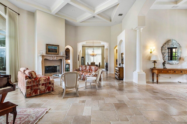 living room with beam ceiling, stone tile flooring, a high ceiling, coffered ceiling, and baseboards