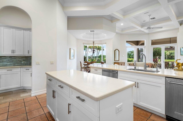 kitchen featuring stainless steel dishwasher, coffered ceiling, a sink, and tasteful backsplash