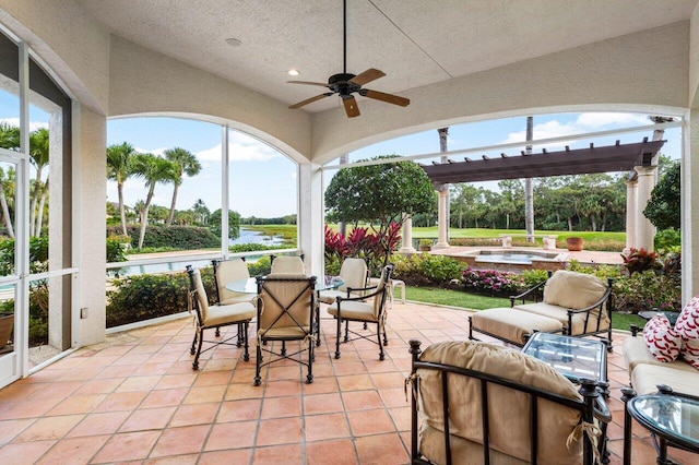 view of patio with an in ground hot tub, outdoor dining area, a water view, and a ceiling fan