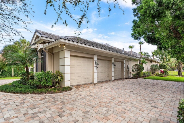 view of side of property featuring a garage, decorative driveway, and stucco siding