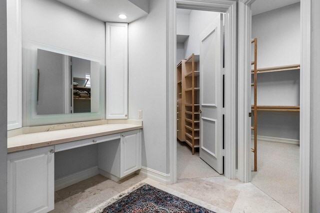 bathroom featuring a spacious closet, vanity, and baseboards