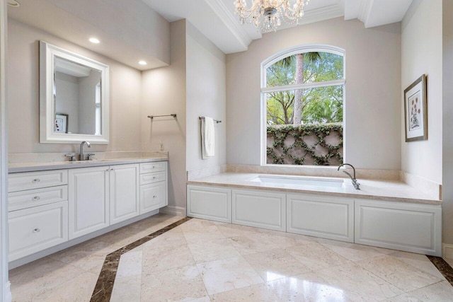 bathroom featuring baseboards, a garden tub, crown molding, vanity, and a chandelier