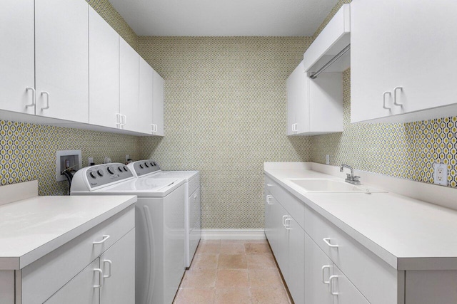 laundry room featuring cabinet space, light tile patterned floors, baseboards, washing machine and dryer, and a sink