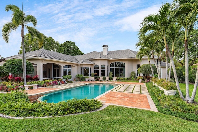 7500 Marsh Cv, Palm Beach Gardens, FL 33418 - back of house featuring stucco siding, a chimney, an outdoor pool, a yard, and a patio area