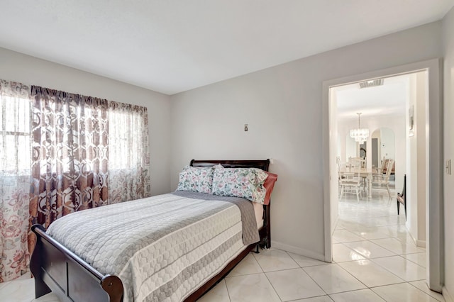 bedroom with light tile patterned floors, arched walkways, visible vents, baseboards, and an inviting chandelier