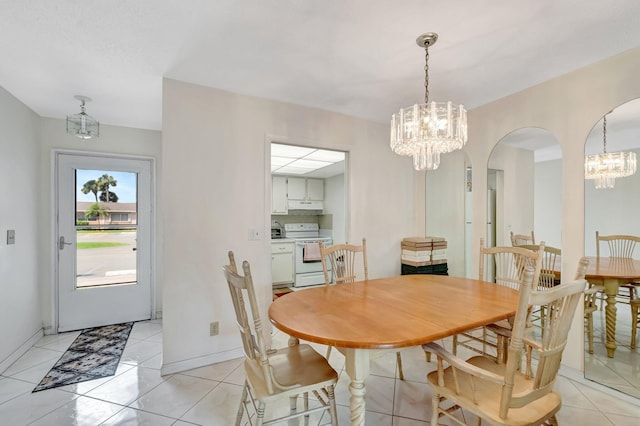 dining room with a chandelier, arched walkways, baseboards, and light tile patterned floors