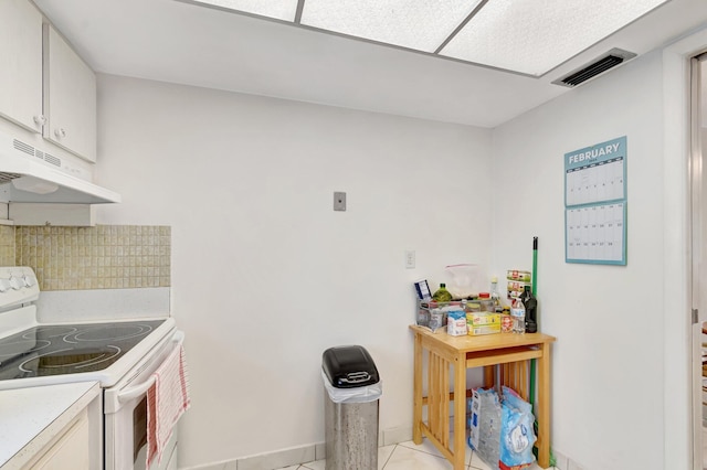 kitchen featuring light tile patterned floors, under cabinet range hood, white electric range, visible vents, and light countertops