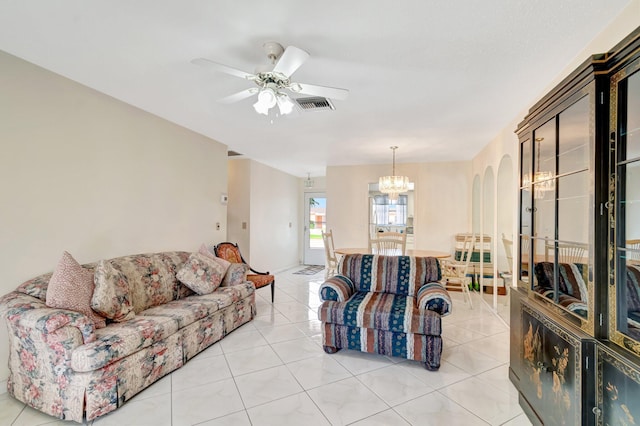 living room with light tile patterned floors, visible vents, arched walkways, and ceiling fan with notable chandelier