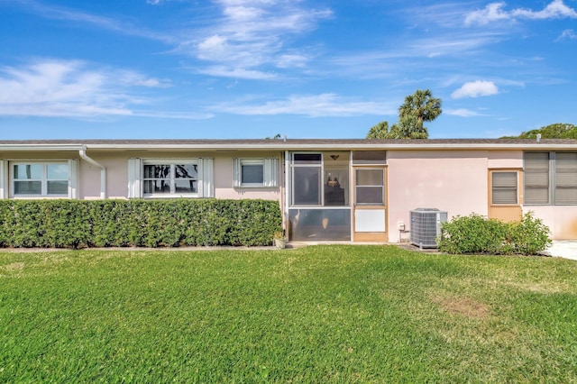 view of front of house featuring a front lawn, central AC, and stucco siding