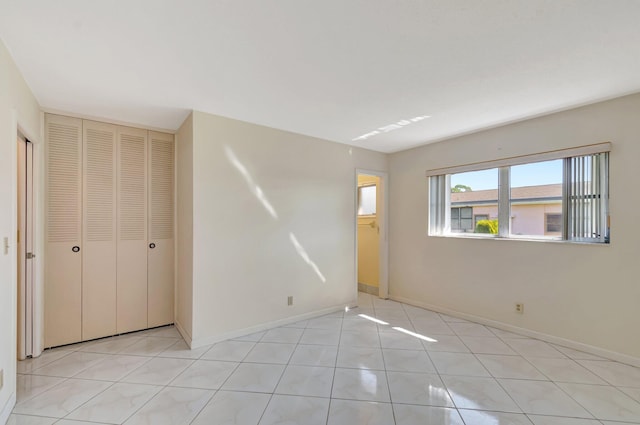 unfurnished bedroom with a closet, baseboards, and light tile patterned floors