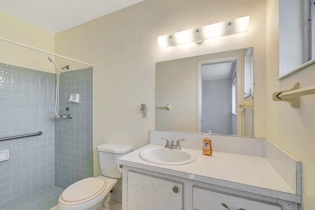 bathroom with tiled shower, vanity, and toilet