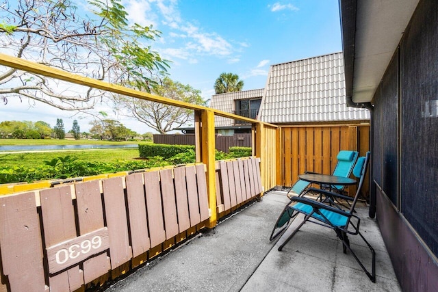view of patio / terrace featuring fence and a water view