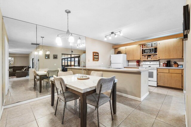 kitchen featuring light countertops, visible vents, white dishwasher, a sink, and a peninsula