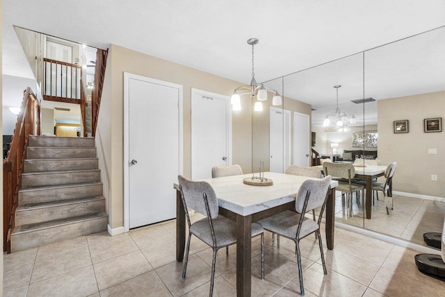 dining space featuring light tile patterned floors, baseboards, a notable chandelier, and stairway