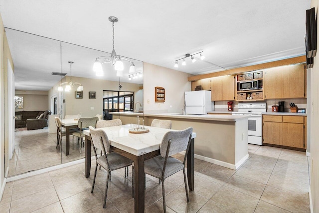 dining area featuring light tile patterned floors, rail lighting, and a notable chandelier