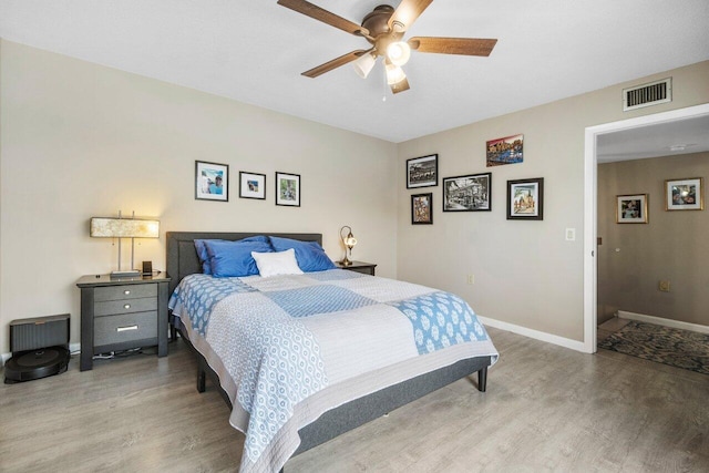 bedroom featuring a ceiling fan, wood finished floors, visible vents, and baseboards