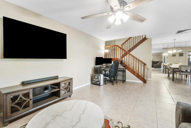 living area featuring baseboards, stairs, light tile patterned flooring, and ceiling fan with notable chandelier