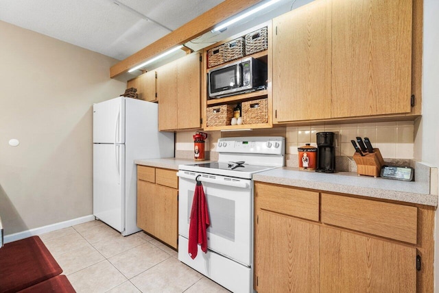 kitchen with tasteful backsplash, white appliances, light tile patterned floors, light countertops, and baseboards