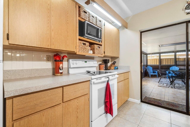 kitchen with stainless steel microwave, light tile patterned floors, white range with electric stovetop, and light countertops