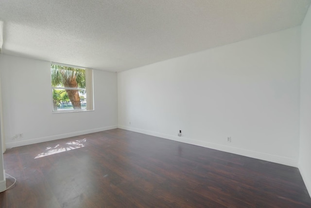 unfurnished room featuring baseboards, dark wood finished floors, and a textured ceiling