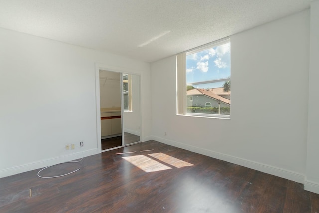 interior space with a closet, a textured ceiling, baseboards, and wood finished floors