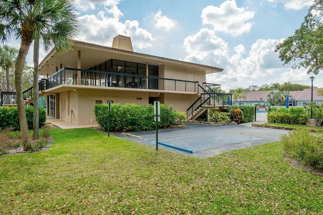 rear view of property featuring stairs, a yard, a chimney, and stucco siding