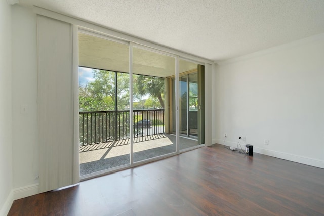 spare room with expansive windows, a textured ceiling, baseboards, and wood finished floors