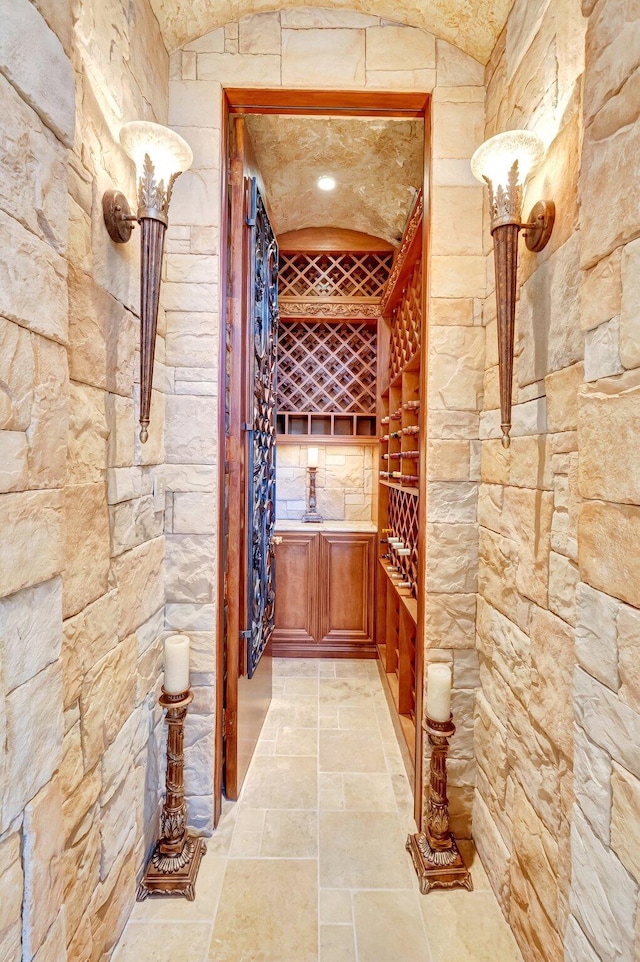 wine area with stone tile flooring and vaulted ceiling
