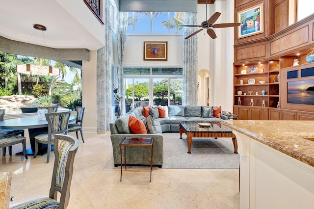 living area with a ceiling fan and a towering ceiling